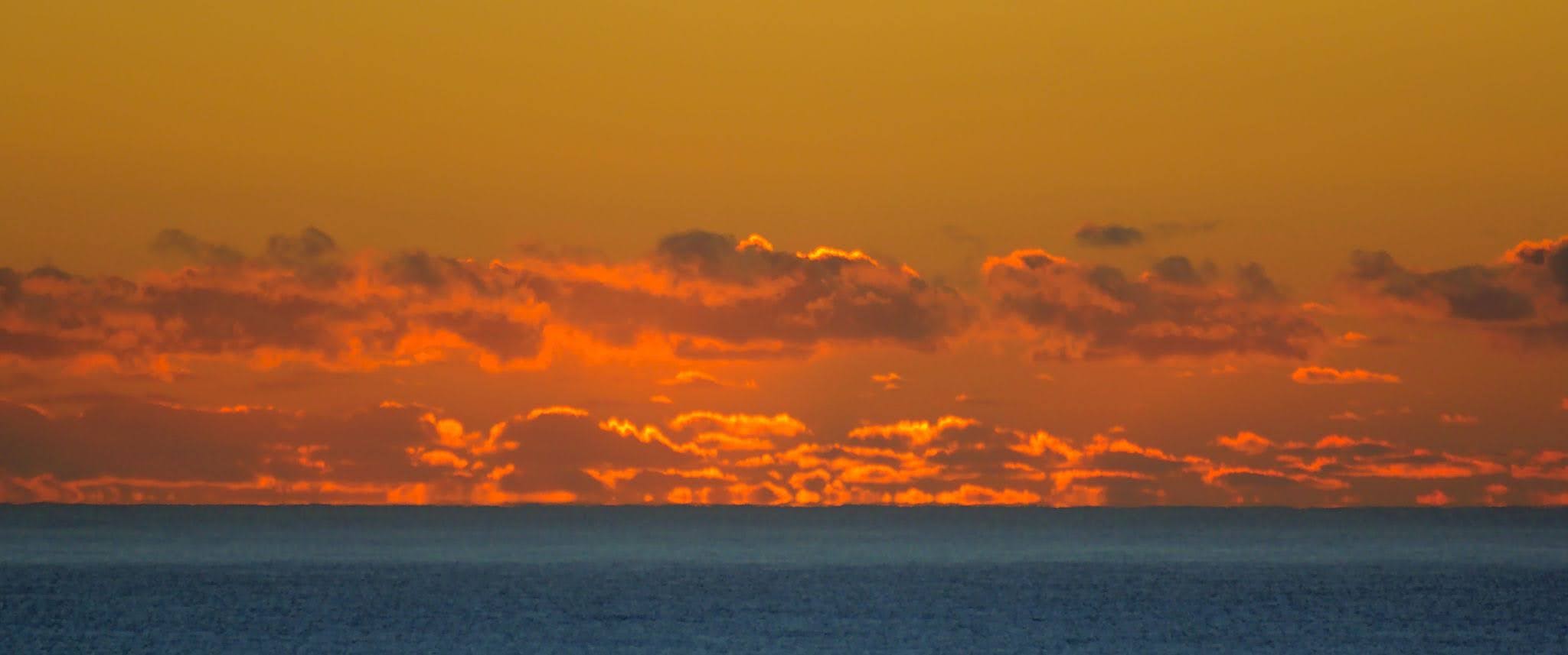 Sunrise cloudscape over the sea in ballito, kwaZulu Natal, South Africa.
The sun is still below the horizon but it is lighting up the clouds to announce that it is about to burst out of the sea.

Taken from Willard Beach in Ballito.